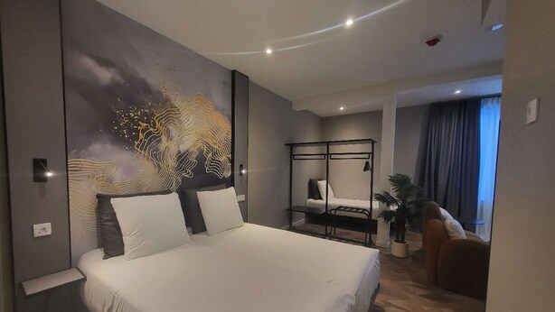 Une chambre d’hôtel moderne avec un grand lit, un bureau, une chaise et une vue sur la ville.