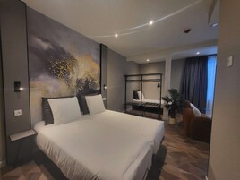 Una habitación de hotel moderna con una cama grande, un escritorio, una silla y vistas a la ciudad.