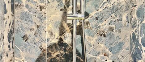 A shower with a rain showerhead and a handheld showerhead, mounted on a chrome stand.