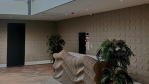 Un hall d’entrée spacieux, doté d’un comptoir d’accueil moderne, d’une grande fenêtre et d’un sol à motifs en chevrons.