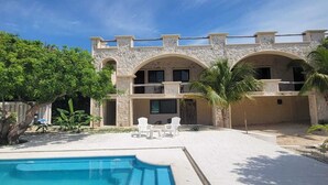 A two-story building with a stone facade, a swimming pool, and outdoor seating.