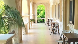 A covered outdoor area with stone walls, a tiled floor, and tables and chairs.