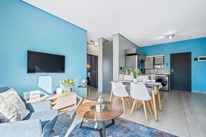 A modern living room with a sofa, coffee table, and dining area with chairs.