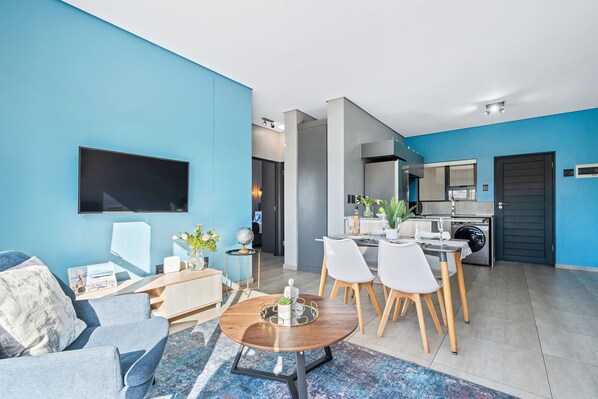 Un salon moderne avec un canapé, une table basse et un coin repas avec des chaises.