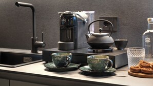 Una cocina moderna con cafetera, hervidor y juego de té sobre la encimera.