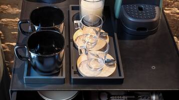 Un coin café équipé d’une machine à café, d’une bouilloire et d’un plateau avec des tasses et une bougie.