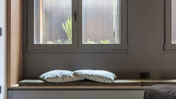 A bedroom with a bed, a window seat with cushions, and a view of the outside.