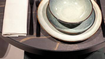 A table set with plates, bowls, glasses, cutlery, and a folded napkin.
