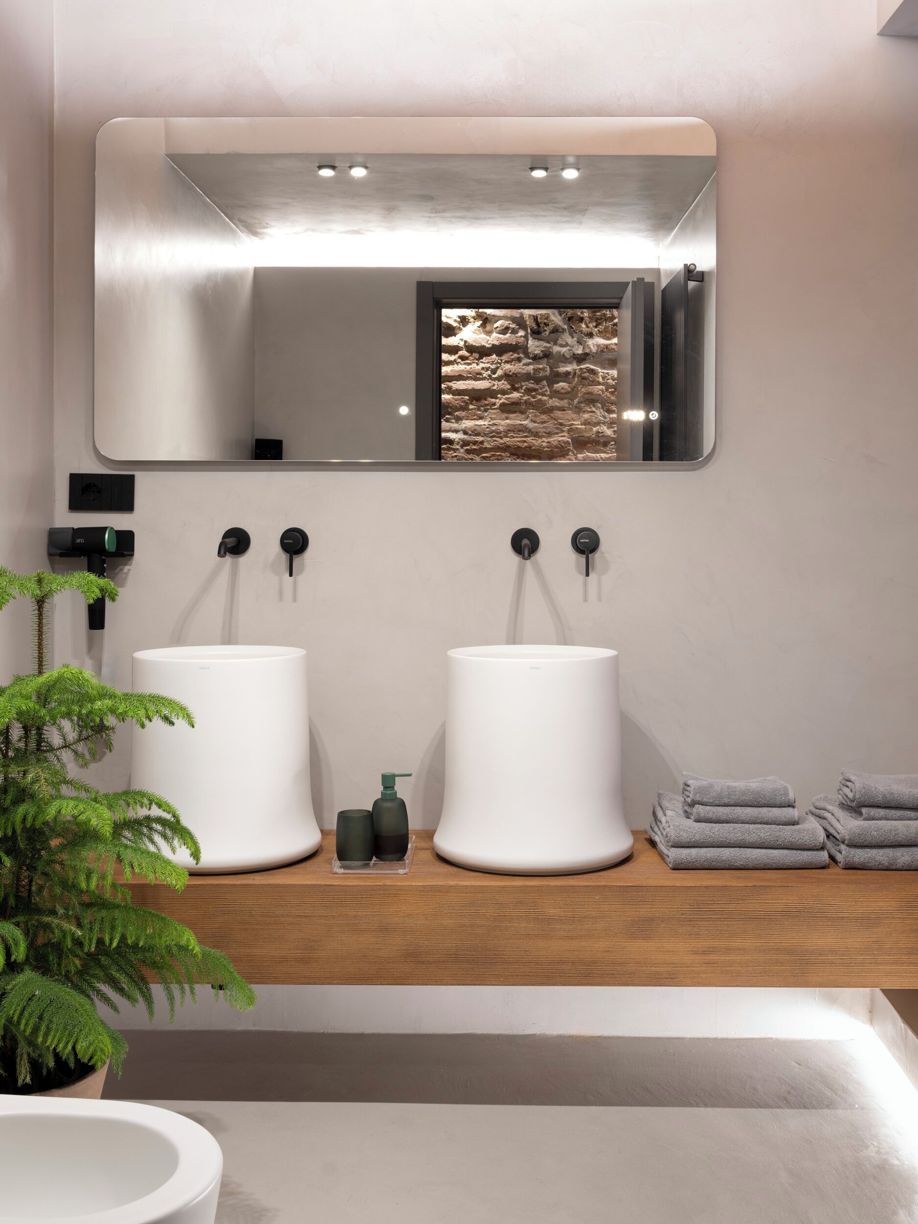 Une salle de bain moderne avec deux lavabos blancs, un grand miroir et un meuble-lavabo en bois.