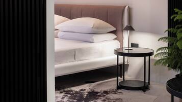 Un dormitorio moderno con cama, mesita de noche, lámpara y planta en maceta.