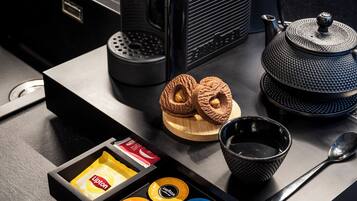 A coffee machine, a teapot, a cup, a spoon, and a drawer with coffee capsules.