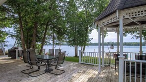 Une terrasse en bois avec une table et des chaises, donnant sur un lac.