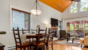 A dining area with a wooden table set for four, surrounded by dark wooden chairs.