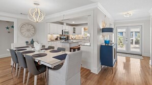 Uma cozinha moderna com armários brancos, uma ilha central e um espaço de jantar com mesa e cadeiras.