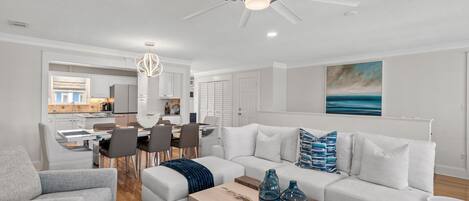 Un salon moderne avec un canapé blanc, une table basse et un coin repas comprenant des chaises et une table.