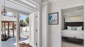 Quarto com cama, um quadro e vista para a área da piscina.