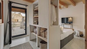 A bedroom with a bed, a TV, and built-in shelving with towels and baskets. - Casa gualta golf emporda costa brava (Gualta)