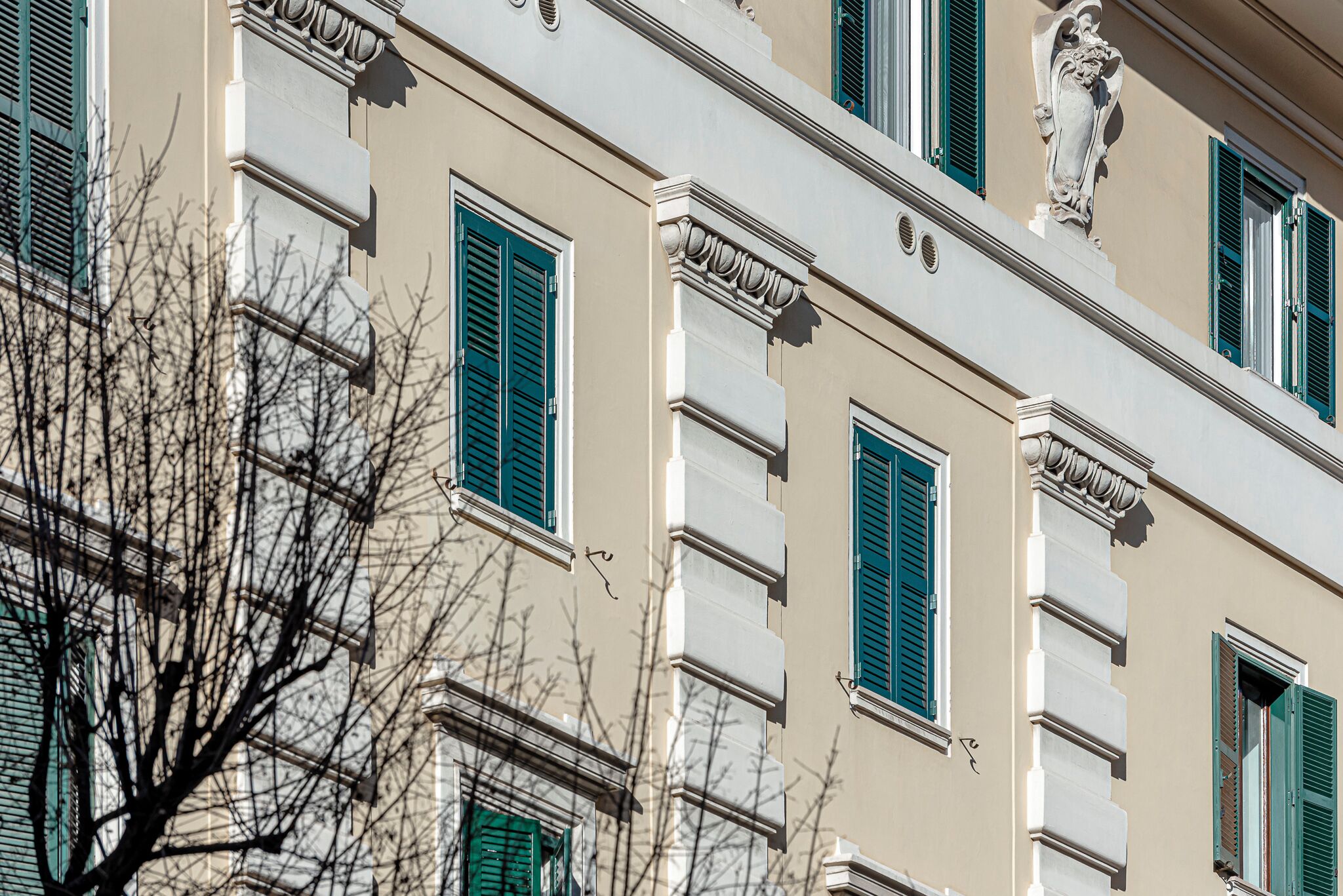 A building facade with multiple windows, some with shutters, and decorative architectural elements.