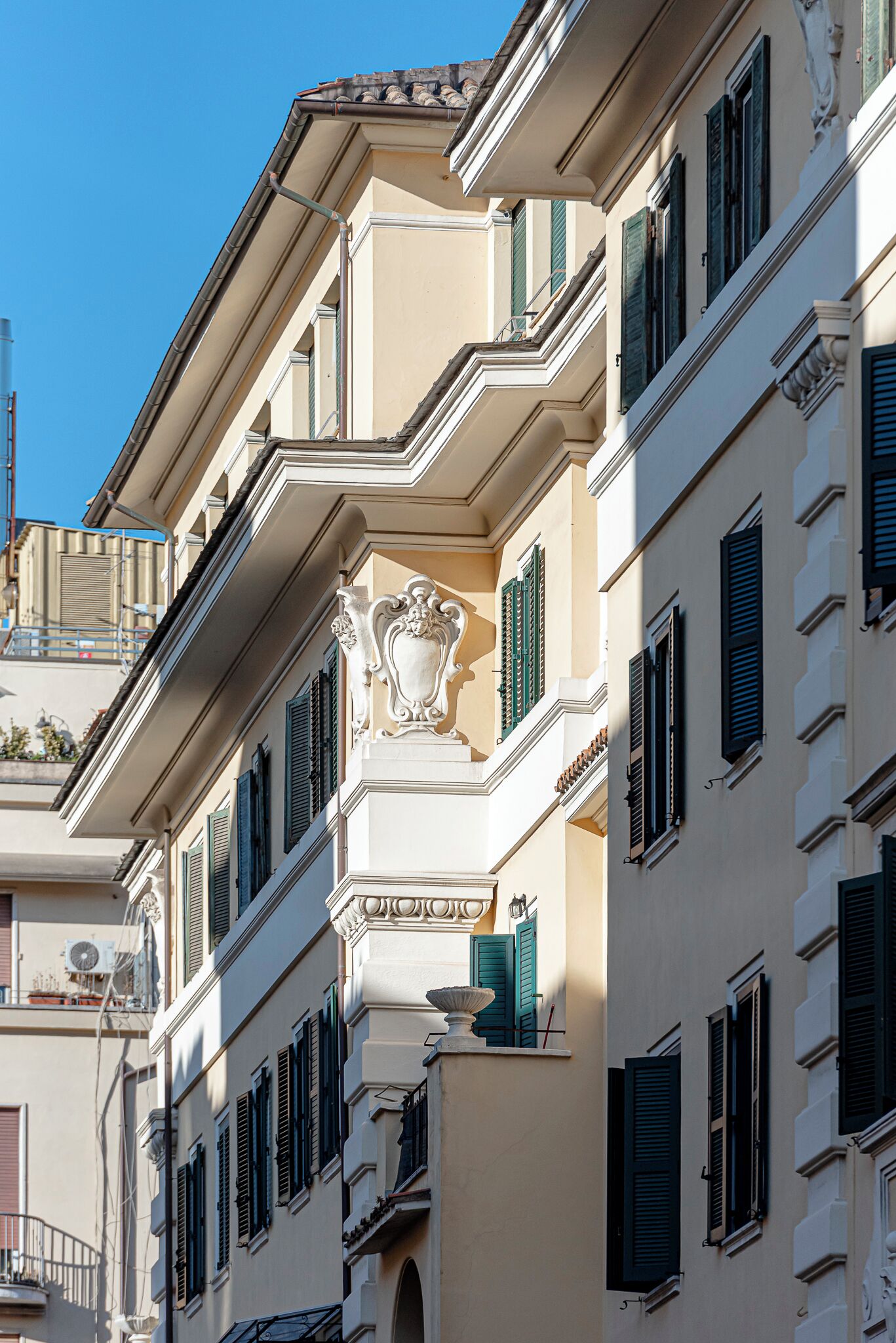 Ein mehrstöckiges Gebäude mit Balkonen, grünen Fensterläden und klassischen architektonischen Details.