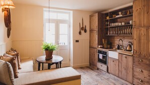 A cozy kitchen with wooden cabinets, a dining area with a bench, and a potted plant. - Pebble Cottage 3, Buckingham Mews (Broadstairs)