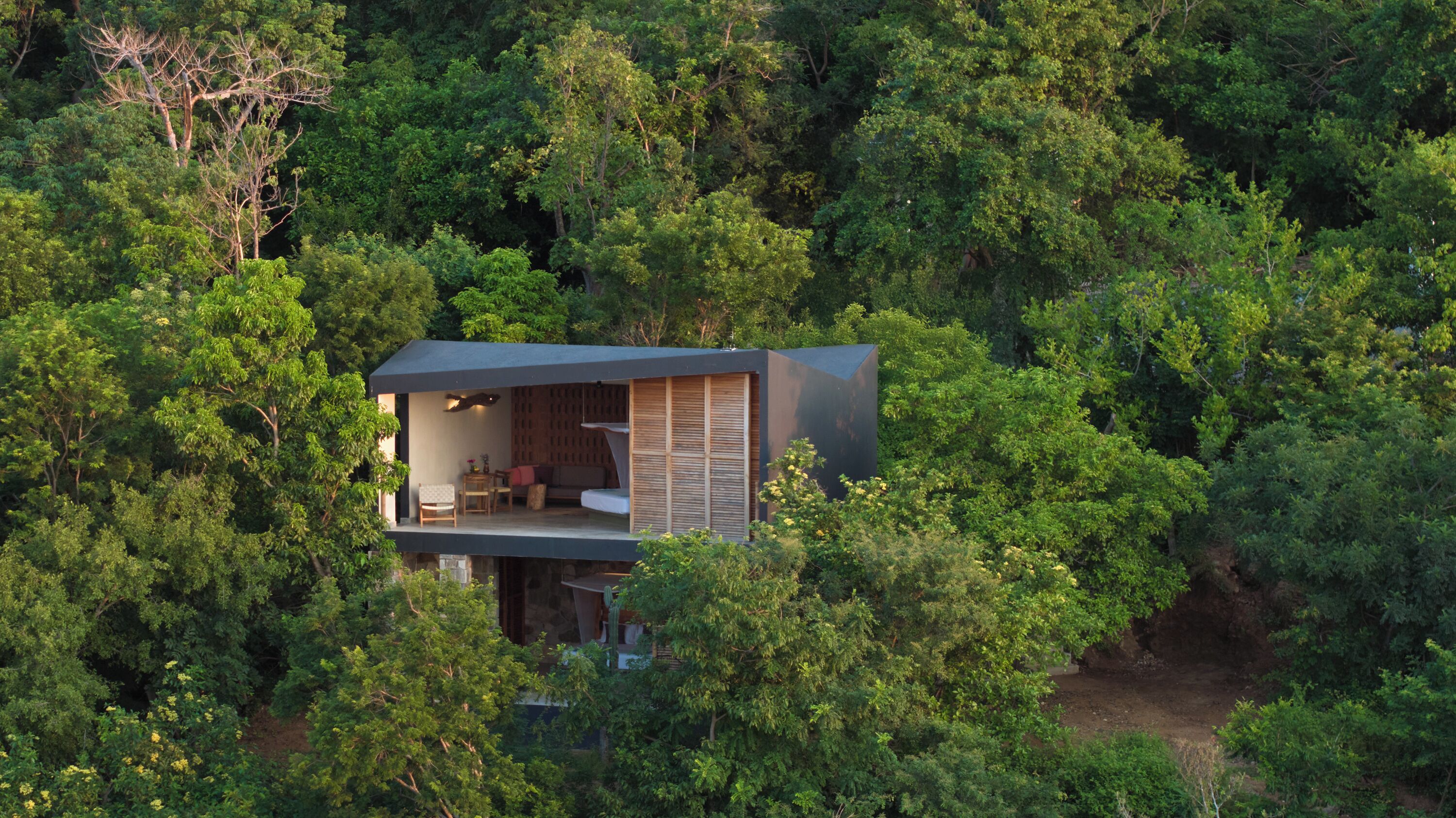 Una casa del árbol moderna con balcón, rodeada de un bosque frondoso.