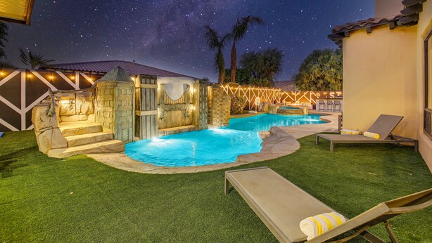 A backyard with a swimming pool, outdoor seating, and a stone structure. - Empire State 7br, Golf, Waterslide, Gamerm (Indio)