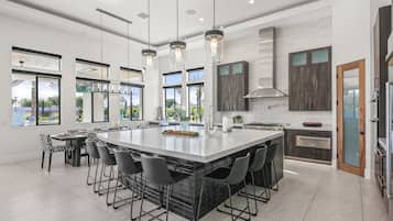 Una cocina amplia con una isla grande, elegantes lámparas colgantes y vistas al exterior.