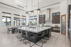 Una cocina amplia con una isla grande, elegantes lámparas colgantes y vistas al exterior.