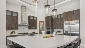 A modern kitchen with a large island, stainless steel appliances, and dark wood cabinets.
