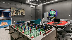 A room with a foosball table, a pool table, and a gaming area with arcade machines. - Pura Vida: Waterslide, Mini Golf, and Games! (Indio)
