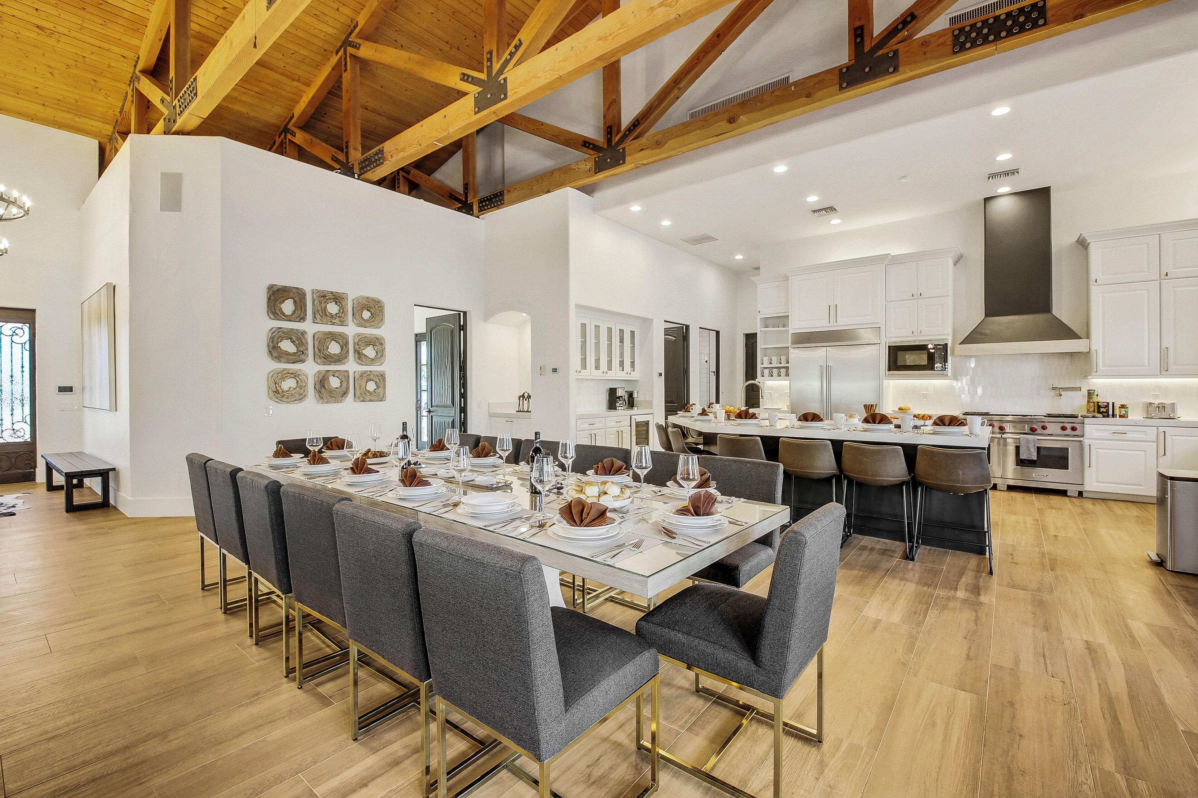 A spacious dining area with a long table set for a meal, surrounded by modern chairs.