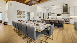 A spacious dining area with a long table set for a meal, surrounded by modern chairs. - The Stallion Estate Sleeps 24, Theater, Game Room, Pickle Ball (Indio)