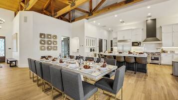 A spacious dining area with a long table set for a meal, surrounded by modern chairs.