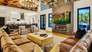 A spacious living area with a large sofa, a coffee table, and a fireplace. - The Stallion Estate Sleeps 24, Theater, Game Room, Pickle Ball (Indio)