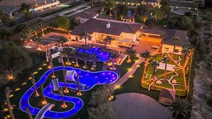 A large house with a swimming pool, surrounded by palm trees and well-lit pathways. - The Stallion Estate Sleeps 24, Theater, Game Room, Pickle Ball (Indio)