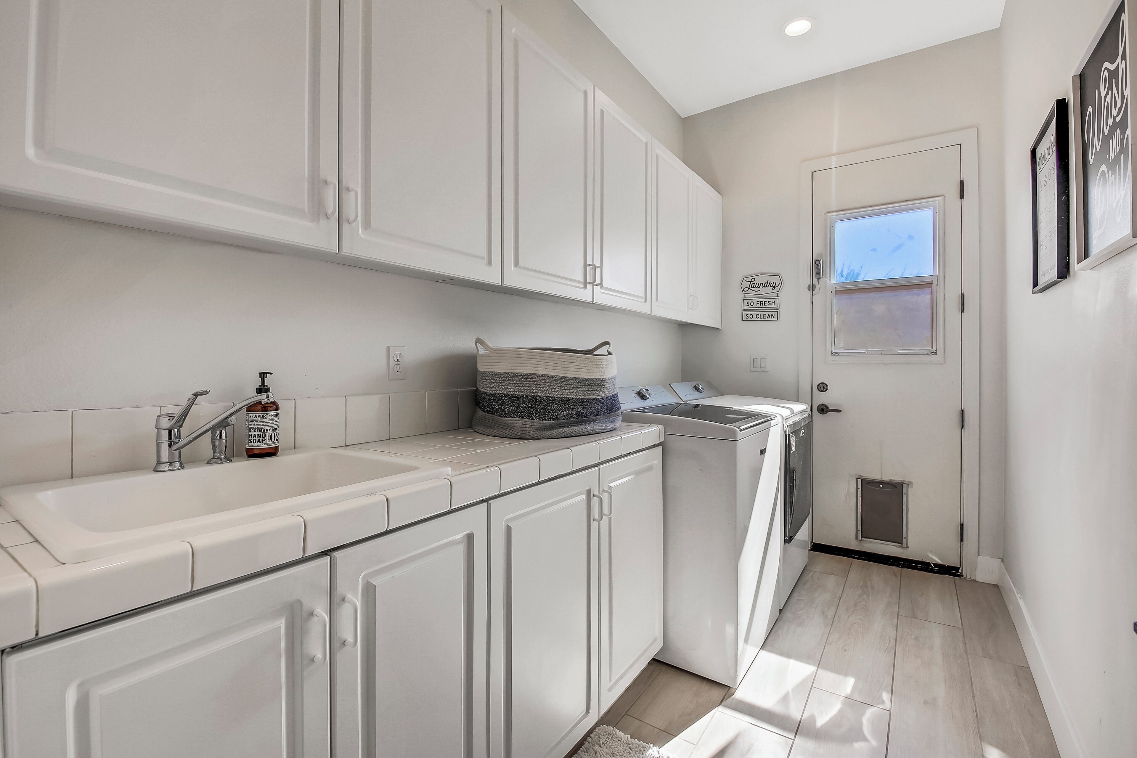 Une cuisine moderne avec des meubles blancs, un évier encastré et un lave-linge.