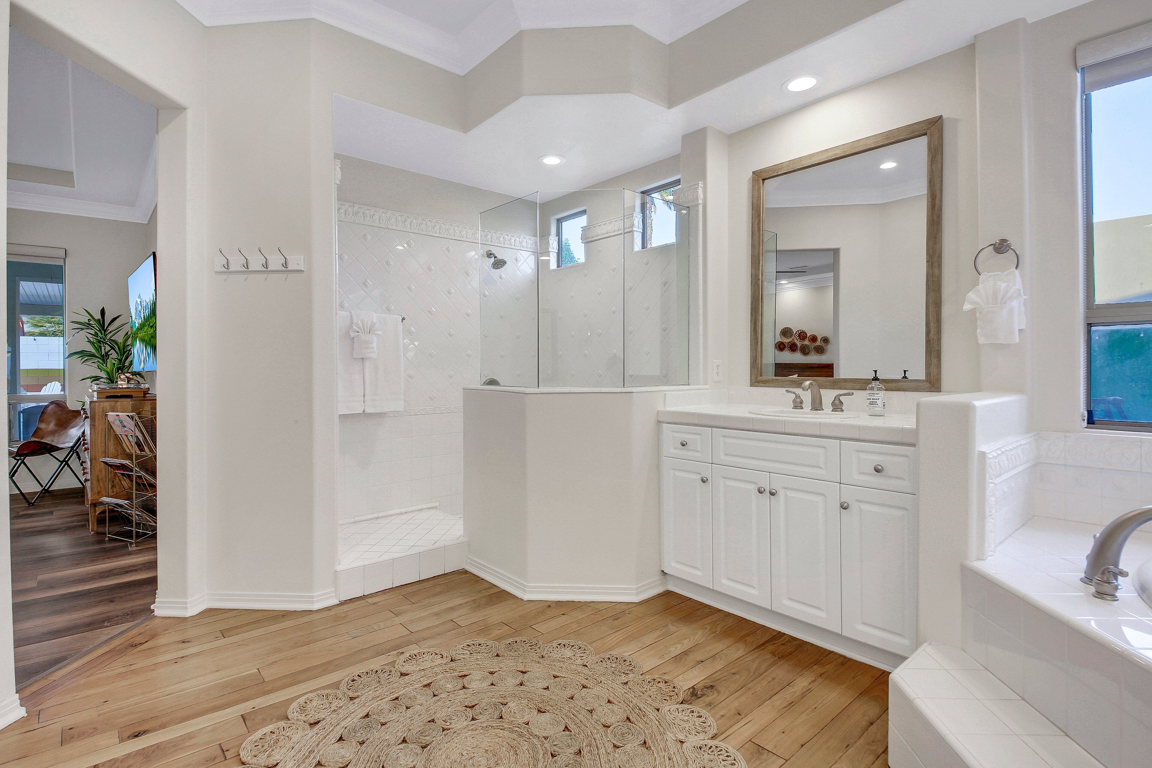 A modern bathroom with a large shower, a double sink vanity, and a large mirror.