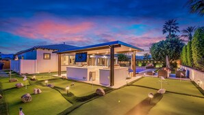 A golf course with a clubhouse, well-manicured lawns, and a sunset sky. - The Montage Resort (Indio)