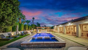 A swimming pool with lounge chairs and a covered patio area. - The Montage Resort (Indio)