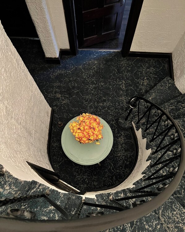 A spiral staircase with a metal handrail and a green plate with flowers at the bottom.
