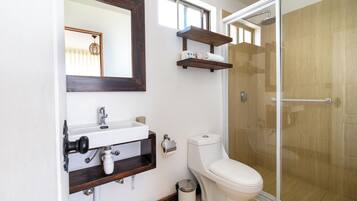 Une salle de bain équipée de toilettes, d’un lavabo, d’un miroir et d’une douche.