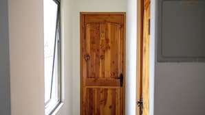 A wooden door with a number '6' sign, a window to the left, and a grey door to the right. - Hostal Geosol (Antofagasta)