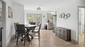 A modern kitchen with a dining area, a refrigerator, and a coffee maker.