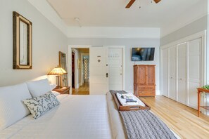 Un dormitorio con cama, mesita de noche, lámpara y televisión en la pared.
