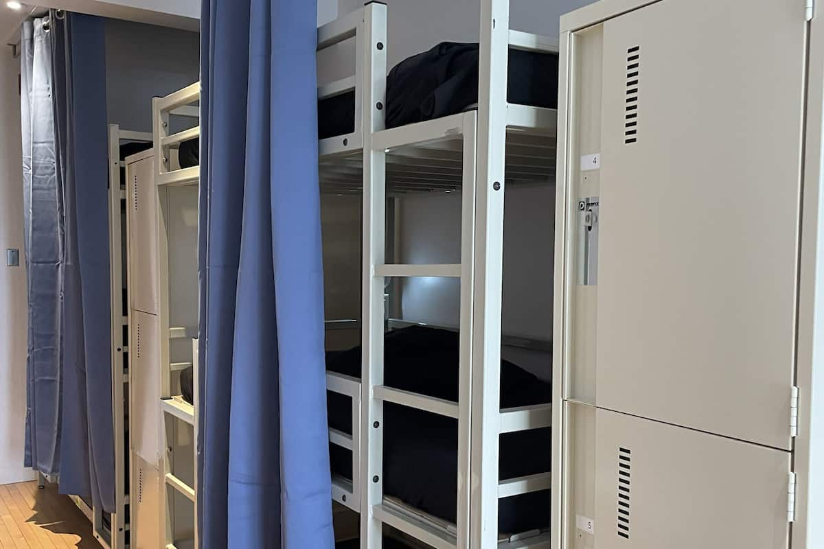 Bunk beds with storage lockers, a wooden floor, and a ceiling light.