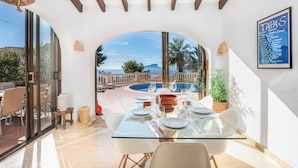 Un espace repas avec une table en verre, des chaises blanches et un tableau affichant le menu intitulé « TAPAS ».