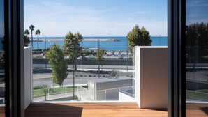A balcony with a view of the sea, a rocky breakwater, and a row of palm trees. - Porta del Mare Luxury Apartment (Salerno)