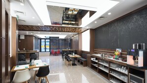 Una cafetería moderna con techo alto, detalles en paneles de madera y una máquina de café.
