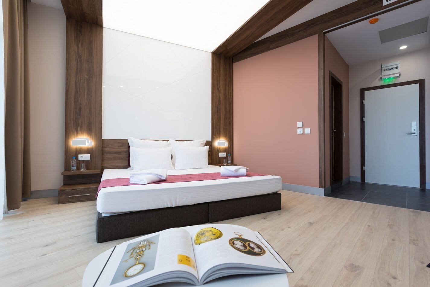 Una habitación de hotel moderna con una cama grande, mesitas de noche y un libro en el suelo.