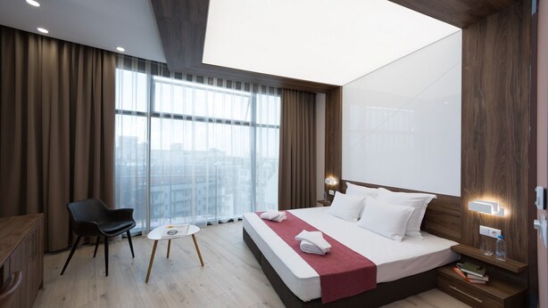 Una habitación de hotel moderna con una cama grande, un escritorio, una silla y una mesita.